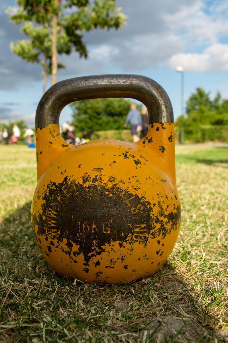 Gelbe Wettkampf-Kettlebell mit 16 Kilogramm steht im Gras